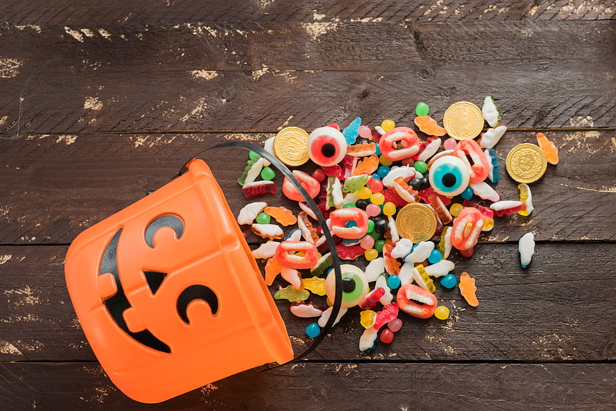 Spilled Halloween Candy from Orange Pumpkin Bucket on Wood