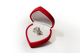 Diamond engagement ring in red heart-shaped jewelry box on white background