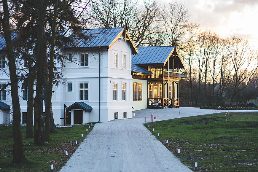 White luxury villa with blue roof and gravel driveway