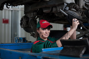 Female mechanic working under car with wrench