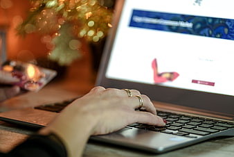 Woman's hand typing on laptop with Christmas tree background