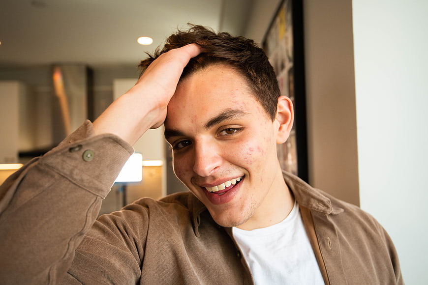 Happy young man smiling with hand on head indoors