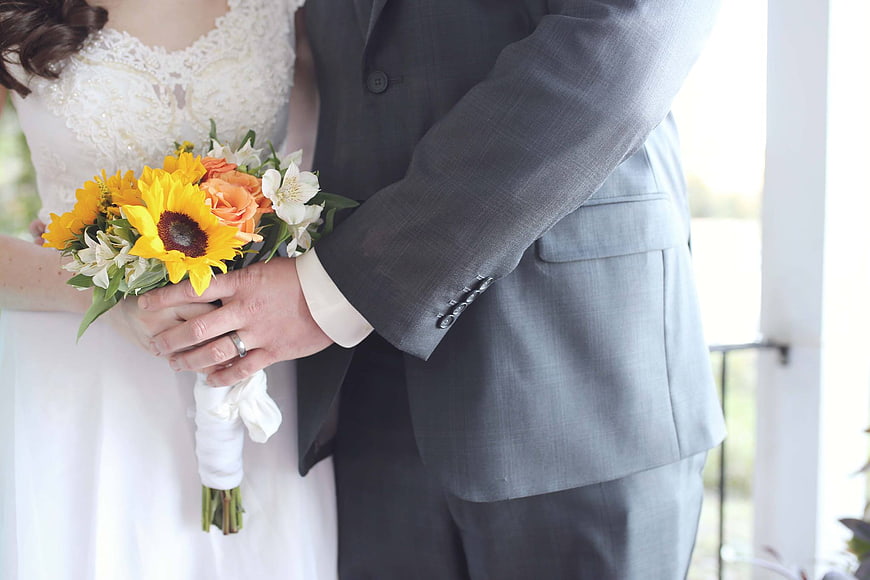 Wedding couple holding sunflower bouquet close-up