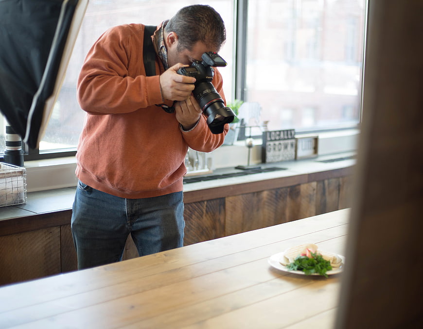 Male photographer shooting food with DSLR camera in kitchen