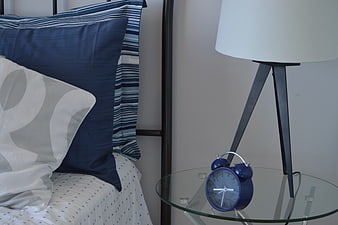 Blue alarm clock on glass nightstand in modern bedroom