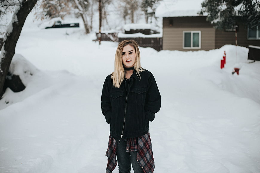 Young woman in winter jacket standing in snowy landscape