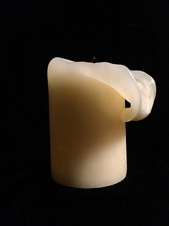 Melted white candle on black background