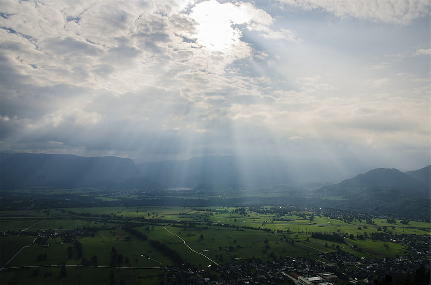 Dramatic sunbeams illuminating a green valley landscape