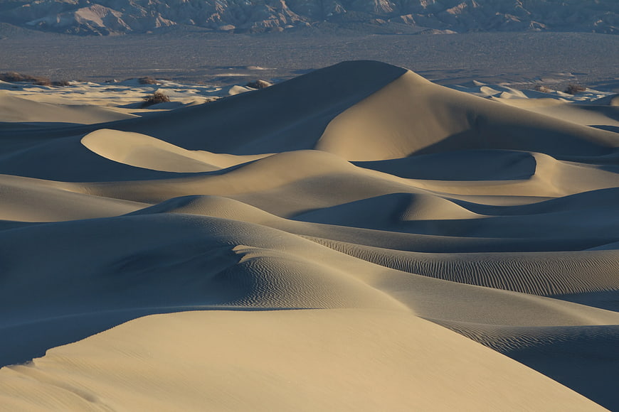 Golden sand dunes with mountains in the background