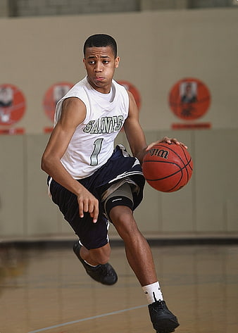 Teenage basketball player dribbling ball in gym