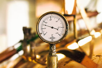 Close-up of vintage industrial pressure gauge on brass pipe