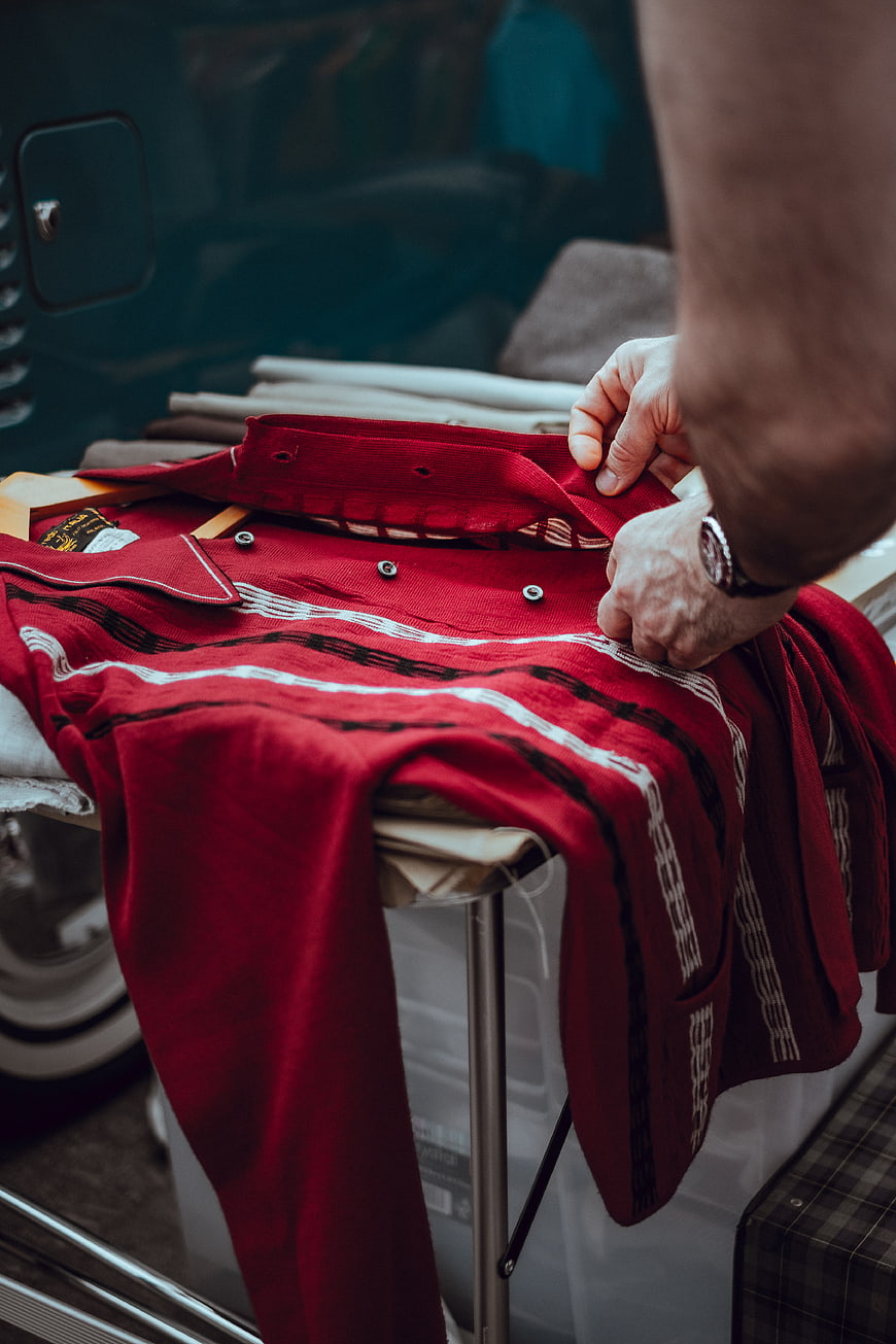 Man inspecting red patterned shirt at outdoor market