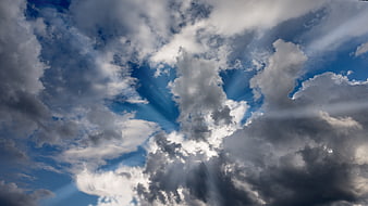 Dramatic Sunbeams Breaking Through Clouds in Blue Sky