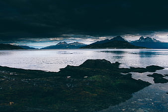 Dramatic moody coastal landscape with dark mountains and calm water