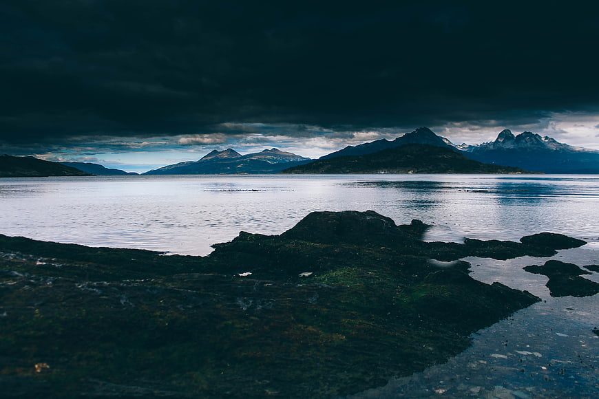 Dramatic moody coastal landscape with dark mountains and calm water