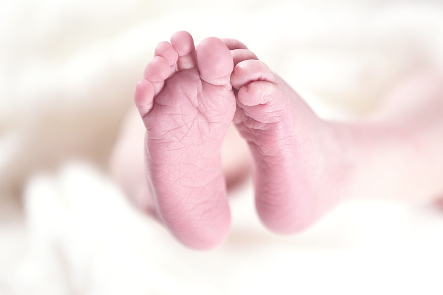 Close-up of newborn baby feet on white blanket