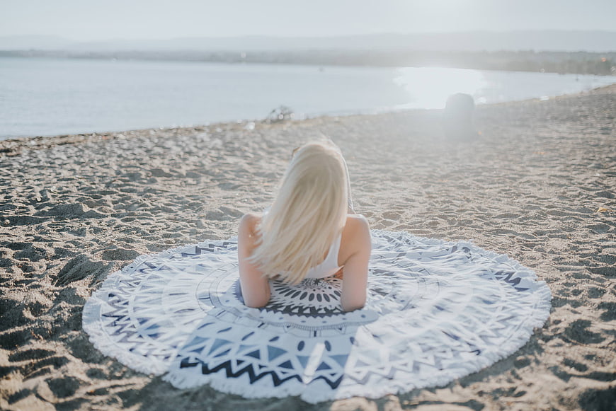 Blonde Woman Relaxing on Patterned Beach Blanket by the Sea