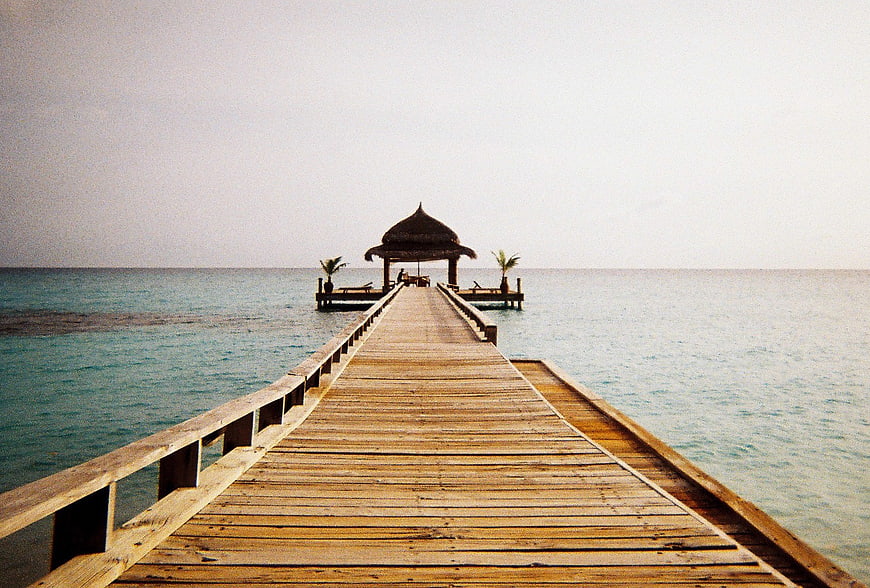 Wooden pier leading to tropical gazebo on calm ocean