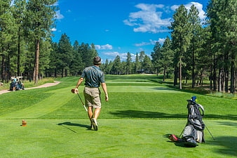 Golfer walking on fairway with golf bag and club