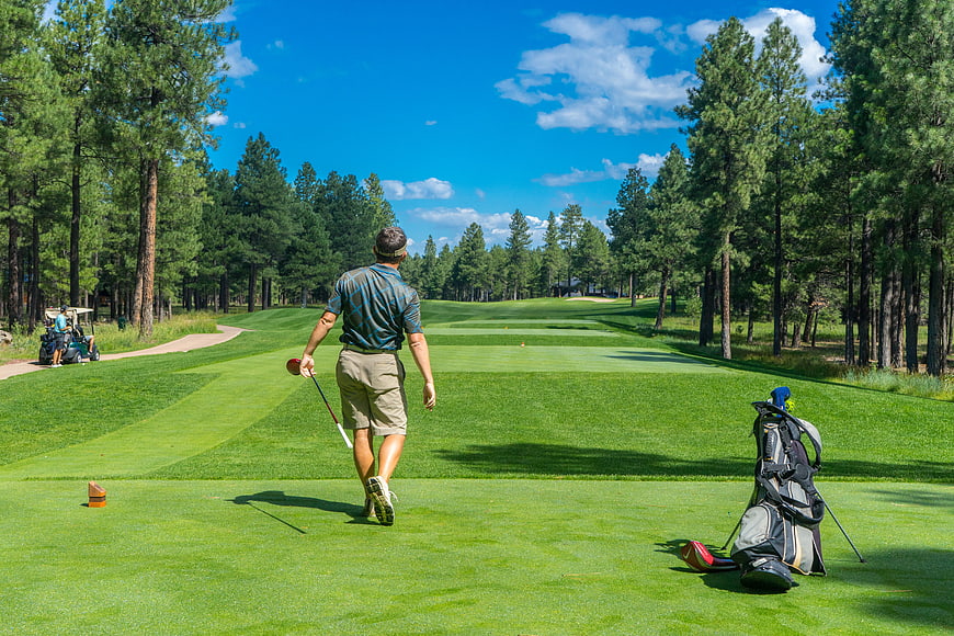 Golfer walking on fairway with golf bag and club