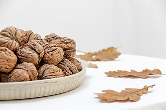 Walnuts in ceramic bowl with autumn oak leaves