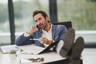Stressed businessman talking on phone with feet on desk