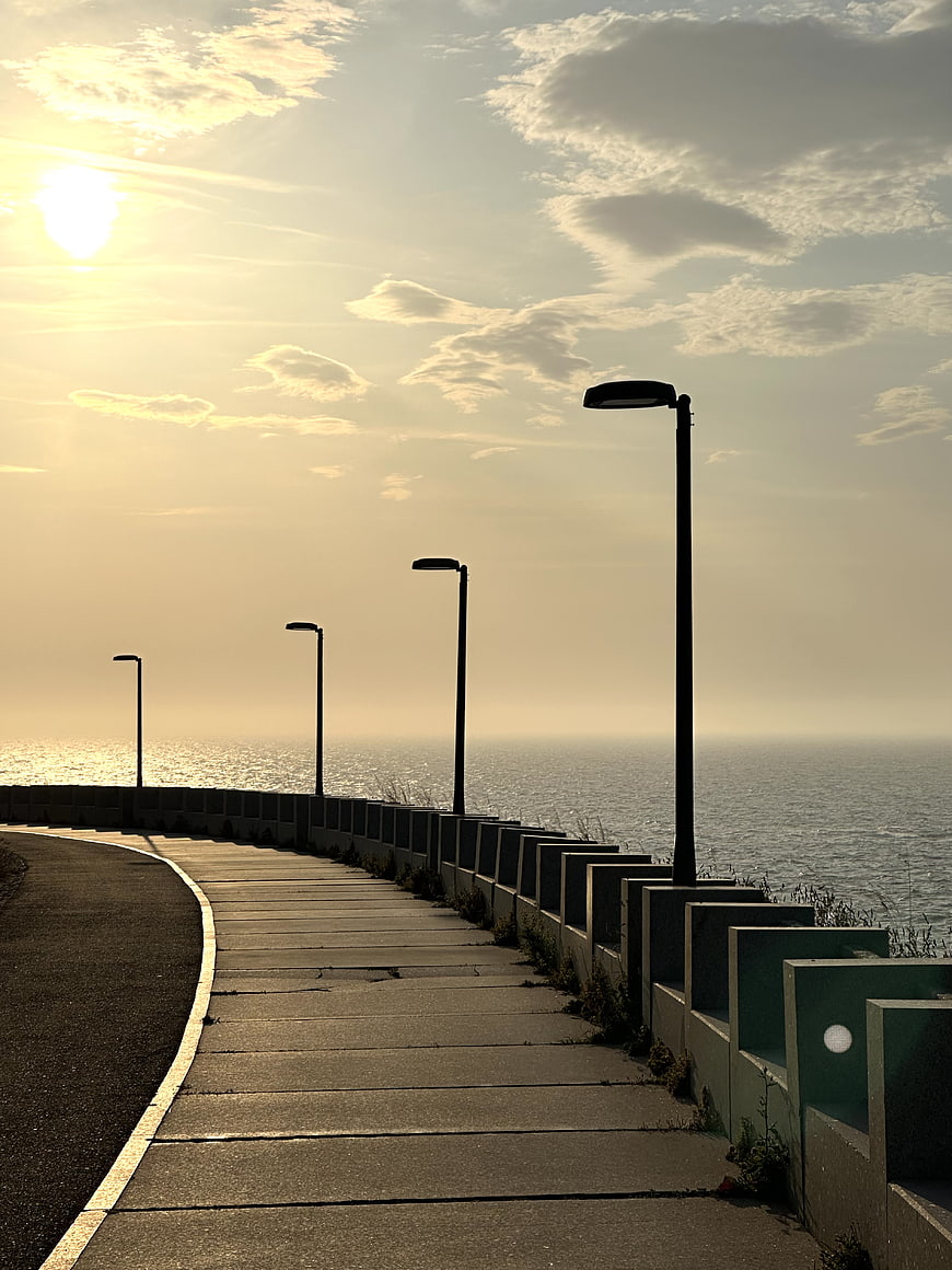 Sunlit Coastal Promenade with Street Lamps and Ocean View