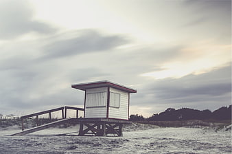 Solitary Lifeguard Tower on Sandy Beach Under Cloudy Sky