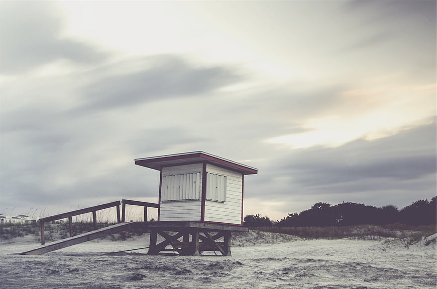 Solitary Lifeguard Tower on Sandy Beach Under Cloudy Sky