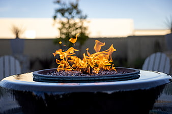 Outdoor fire pit with flames on a patio at dusk