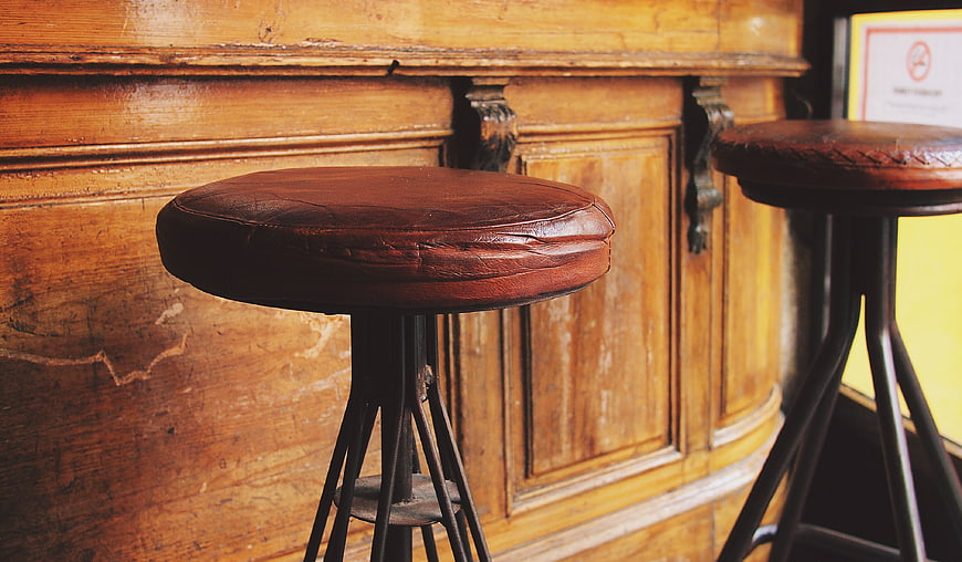 Vintage leather bar stools against rustic wooden paneling