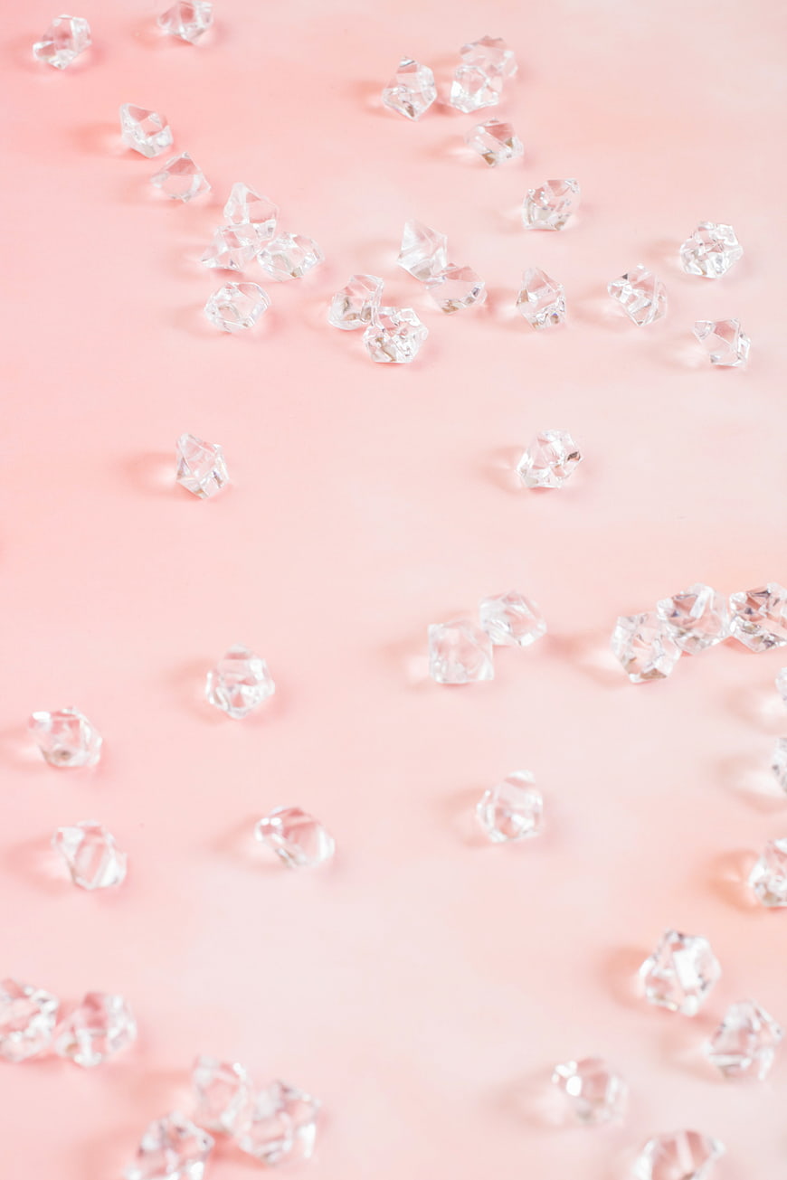 Scattered clear gemstones on pastel pink background