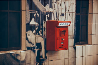 Red Police Alarm Box on Tiled Wall with Graffiti