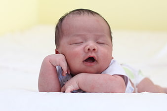 Sleeping newborn baby yawning on white blanket