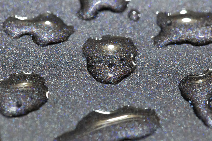 Macro water droplets on glittery dark surface