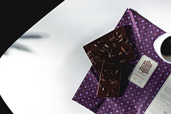 Top view of dark chocolate bars with coffee on purple paper