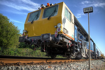 Yellow Freight Train on Tracks with Blue Sky