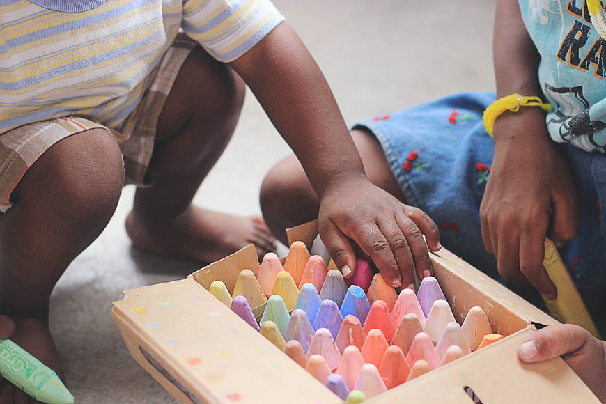Children Playing with Colorful Crayons in a Box