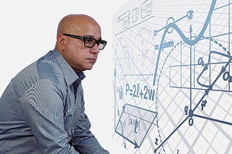 Bald man with glasses analyzing complex physics equations and diagrams