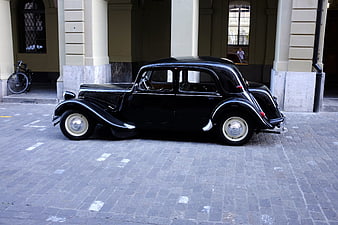Vintage black classic car parked on cobblestone street
