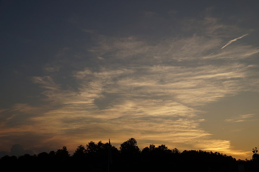 Dramatic sunset sky with textured clouds and tree silhouette