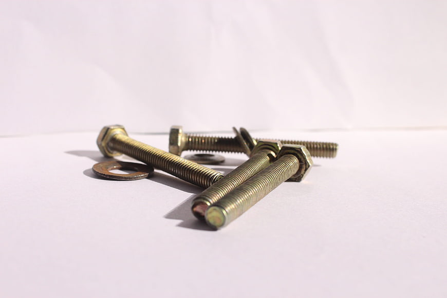 Close-up of brass hex bolts and washers on white background