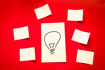 Hand-drawn lightbulb on sticky note surrounded by blank notes on red background