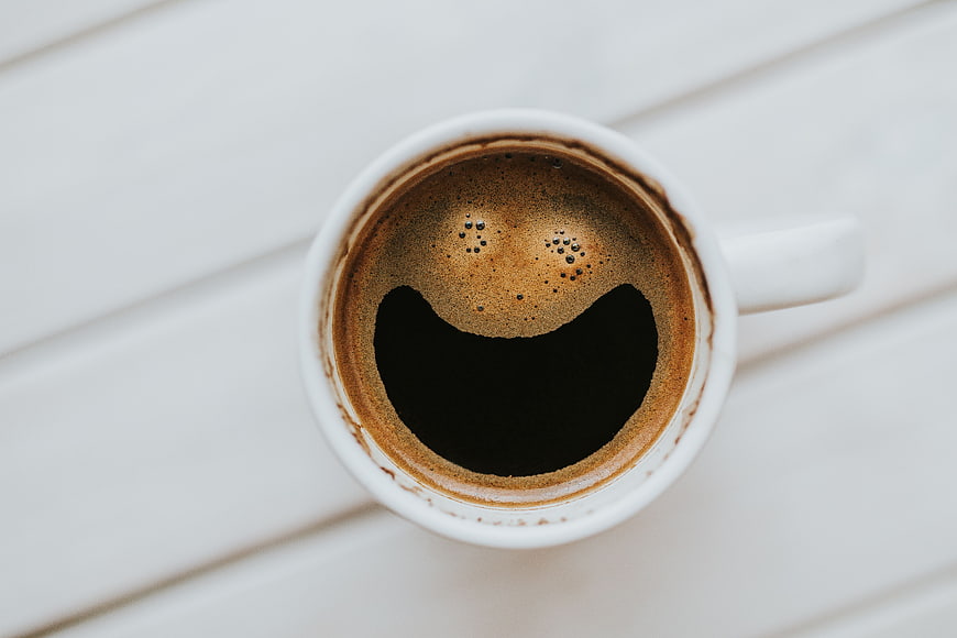 Top view of black coffee in white cup on white table