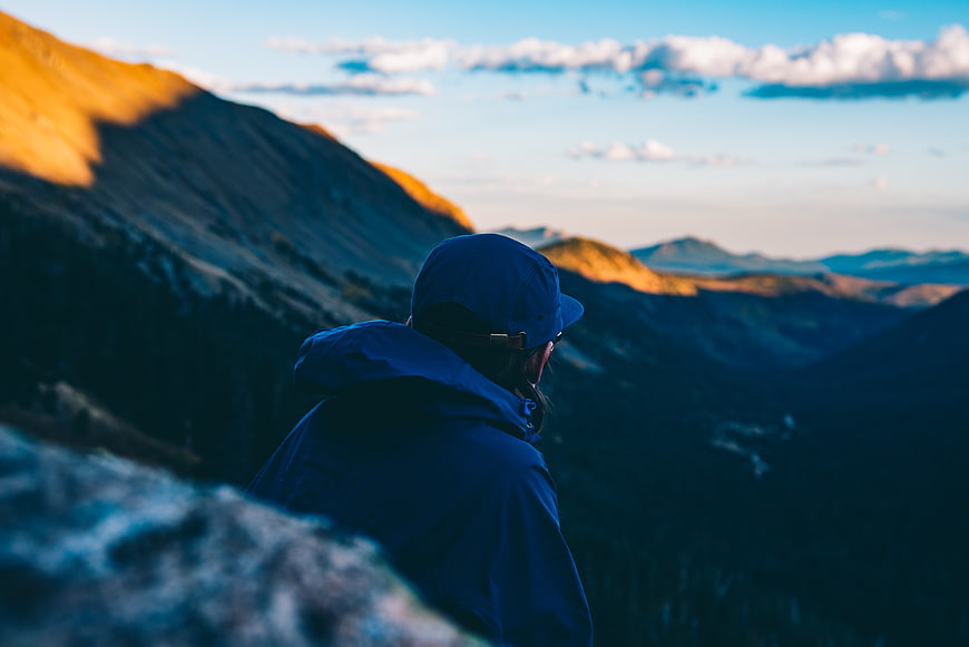 Hiker in Blue Jacket Overlooking Mountain Valley at Sunset