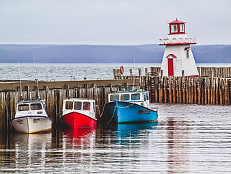 Colorful Fishing Boats Docked Near Red and White Lighthouse