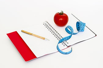 Diet planning concept with tomato, notebook, pen, and measuring tape