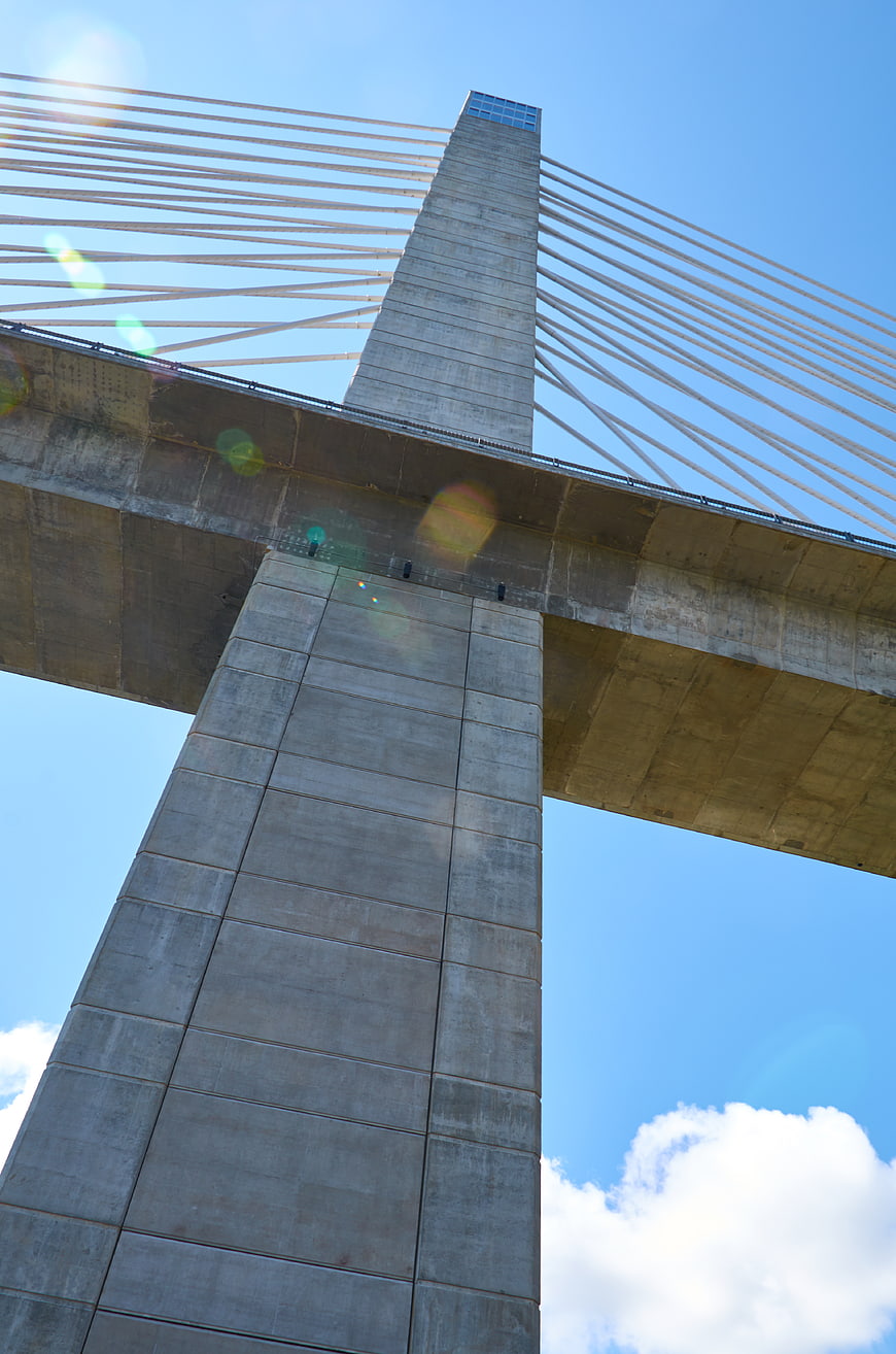 Low angle view of concrete cable-stayed bridge tower against blue sky