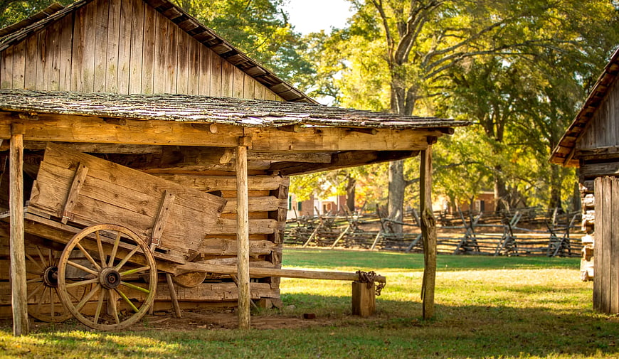 Vintage wooden wagon under rustic log cabin porch in autumn