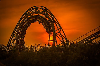 Roller Coaster Loop Silhouette Against Dramatic Orange Sunset Sky